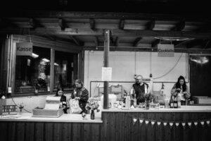 Bar, die Personen zeigt für den Cocktailausschank und hinter einer Kasse.