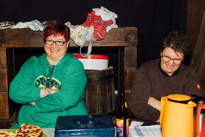 zwei lachende Frauen, die hinter der Kuchentheke sitzen