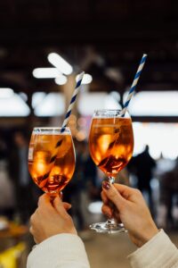 zwei hochgehobene und gefüllte Weingläser, in denen sich das Licht spiegelt