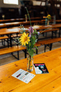 Blumenstrauß auf einer Bierbank mit Kelterfestival Flyern