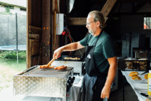 Helfer beim Grillen von Würsten