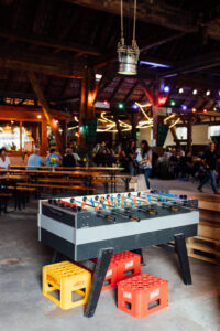 Impression der Kelter mit Tischkicker, Bierbänken und Menschen im Hintergrund